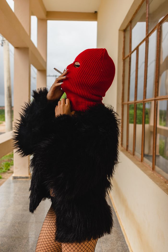 The Art of Drawing Readers In: Your attractive post title goes here A person in a furry jacket and red balaclava smokes outdoors, side view perspective.
